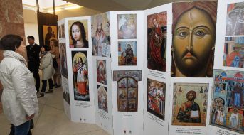 Відвідувачка виставки розглядає стенд із зображеннями ікон