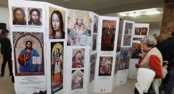 Відвідувачка виставки розглядає стенд із зображеннями ікон