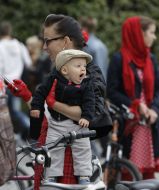The participant of cycle race holds a child on hands