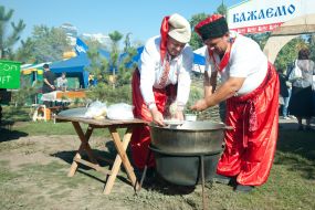Men in costumes of cossack near the auldron of kulish