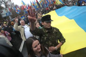Участники Марша борьбы несут развернутый украинский флаг