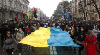 Участники Марша борьбы несут развернутый украинский флаг