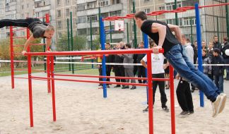Young people perform exercises on crossbar