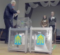 Мужчина бросает бюллетень в урну для голосования