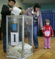 Жінка кидає бюлетень в урну для голосовання