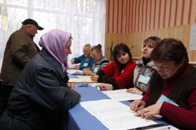 Пожилая женщина получает бюллетень для голосования
