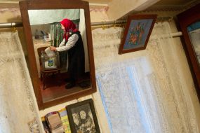 Пожилая женщина опускает бюллетень для голосования в урну