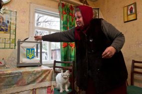 Женщина опускает бюллетень для голосования в урну