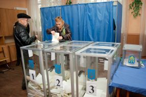 Женщина бросает бюллетени для голосования в урну