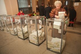 Женщина бросает бюллетени для голосования в урну