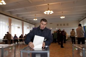 Милиционер опускает бюллетень в урну для голосования