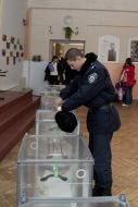 Милиционер опускает бюллетень в урну для голосования