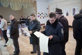 Избиратели рассматривают бюллетени для голосования