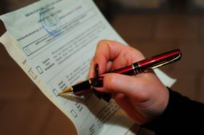 Женщина ставит отметку в бюллетене для голосования