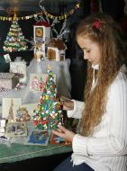 Девочка рассматривает бумажную елочку