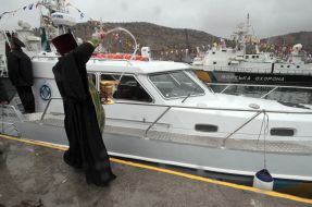 Священник окропляет святой водой катер