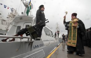 Священник окропляет святой водой катер