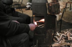 Man throws wood into "stove"