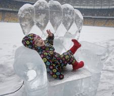 Ребенок сидит на ледовой фигуре в виде кресла