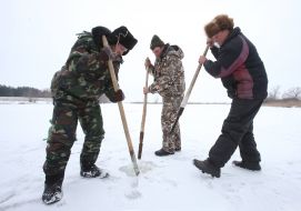 Мужчины делают лунки во льду