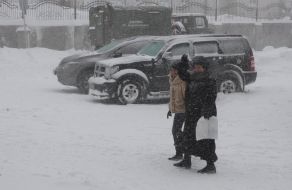 Прохожие идут по заснеженной улице