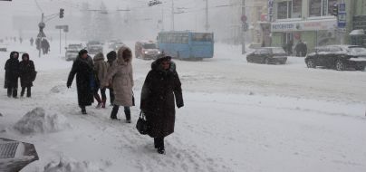 Прохожие идут по заснеженной улице