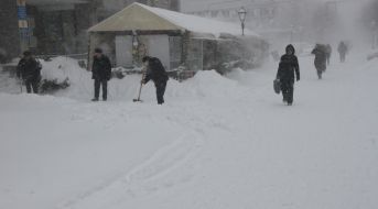 Прохожие идут по заснеженной улице