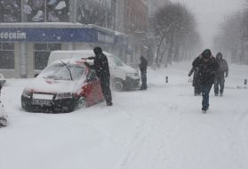 Прохожие идут по заснеженной улице