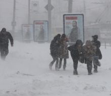 Прохожие идут по заснеженной улице