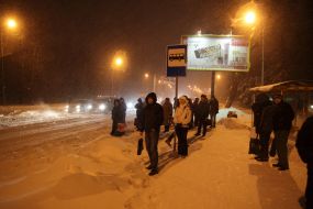 Люди стоят на остановке в ожидании транспорта