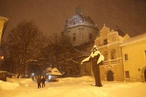 Прохожие идут по заснеженной улице