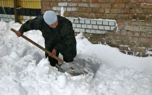 Женщина расчищает дорогу от снега