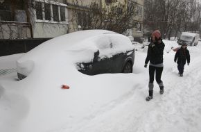 Люди проходят возле засыпанного снегом автомобиля