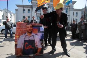 A man throws  tomatoes to a portrait of Ivan Urganta