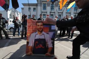 A man throws  tomatoes to a portrait of Ivan Urganta