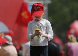 Girl in a cap with communist symbols weaves a wreath of dandelions