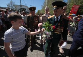 The boy gives flowers to veteran