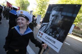 A boy holds a portrait of Soviet Union Hero