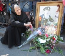 A woman sits next to a portrait of WWII's website