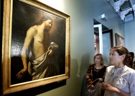 A girl stands near the "Jesus Christ" picture