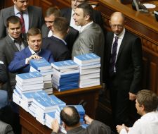 Депутаты складывают экземпляры послания Президента на трибуне