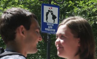 Молодые люди возле дорожного знака  "Место для поцелуев"