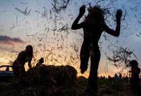 Girl jumping through a haystack