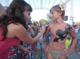 Woman paints boy the mud