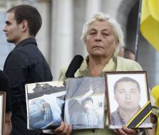 A woman holds a portrait of son