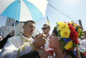 Священник причащає вірянку