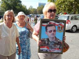 Жінка тримає в руках портрет президента Сирії