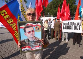 Жінка тримає в руках портрет президента Сирії