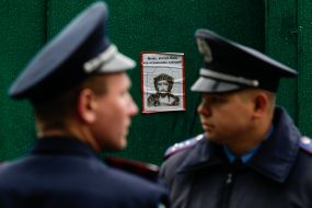 Militiamen stand near the poster