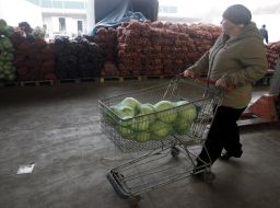 A woman carries the cart with a bag of cabbage